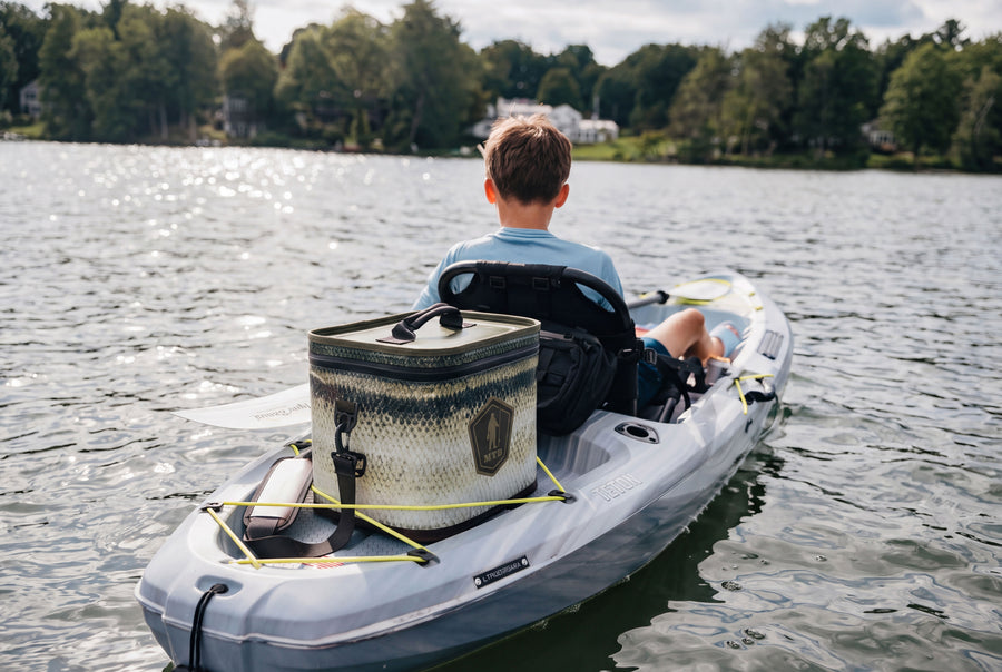 Young angler holding a largemouth bass next to the Scale Series Soft Cooler