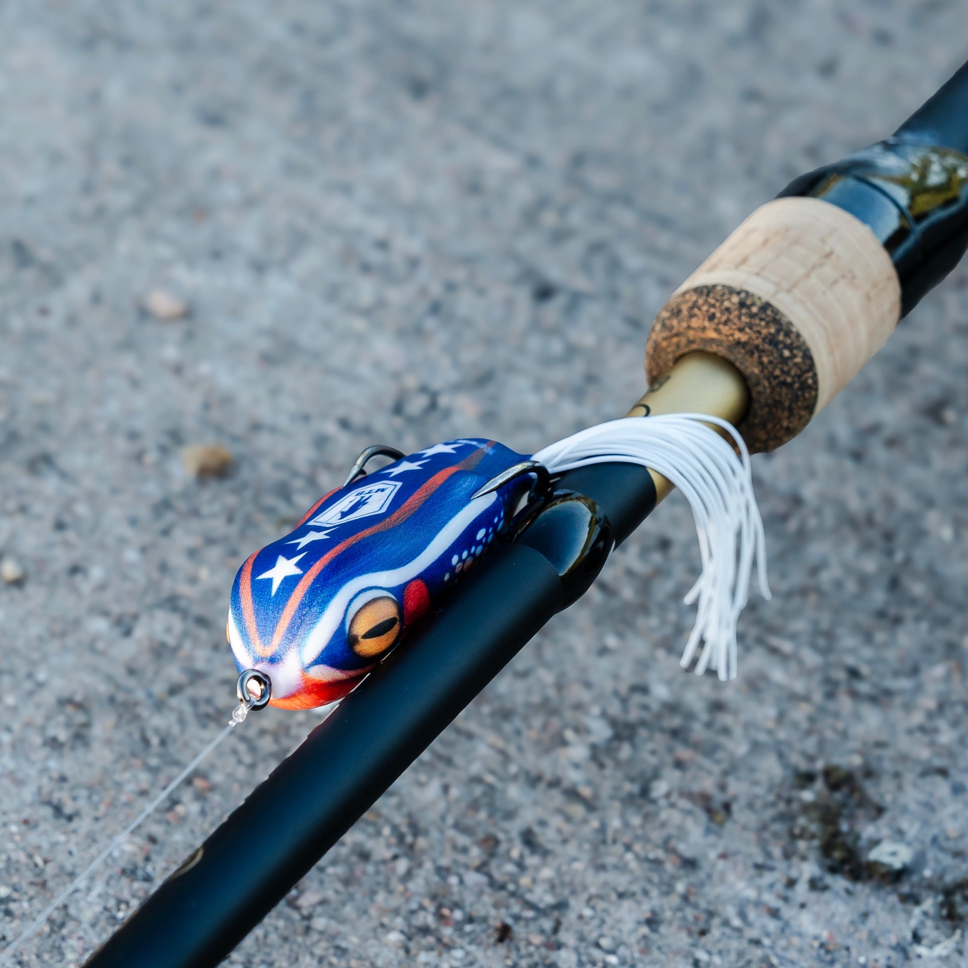 Fishing rod with a colorful lure on a gray surface